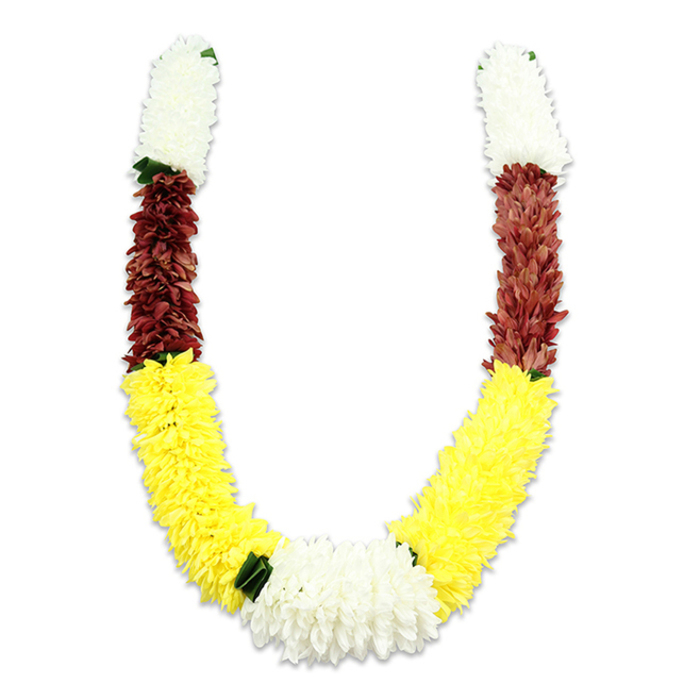 A vividly coloured, U-shaped mala of artificial flowers sits against a pure white backdrop, photographed in soft light that accentuates its texture and shape. From the top of each arm a plush band of creamy white, tightly clustered small petals begins the composition, conveying a delicate, almost feathery softness that suggests chrysanthemum or jasmine forms. Directly beneath these white sections a concentrated swathe of dark maroon or reddish-brown provides a rich contrast, its densely packed petals offering a sense of weight and solemnity. The longest and most expansive portion of each arm is a vibrant yellow band: bright, cheerful, and voluminous, those yellow fabric blooms are arranged to produce a full, flowing curve that defines the 'U'. At the centre bottom where the two yellow bands meet, a wider cluster of pure white chrysanthemum-like flowers creates the composition's focal knot, framed and punctuated by small dark green leaf-like accents that mark the transitions between colour blocks. The meticulous craftsmanship-thousands of fabric petals layered and shaped to mimic living blooms-speaks to a piece built to last for repeated ceremonial use. In Somers Town such garlands are typically requested for Hindu poojas, temple offerings, wedding ceremonies, and festivals like Diwali and Holi, where their colours carry specific meaning: white for purity, yellow for prosperity, and maroon for devotion. The image conveys both celebration and ritual respect, practical durability and enduring cultural significance, suited to ceremonial placement or as an offering in local temples and community gatherings around Judd Street and Granby Terrace.